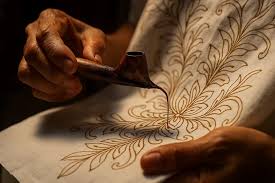 Tangan perajin mengaplikasikan canting pada kain batik